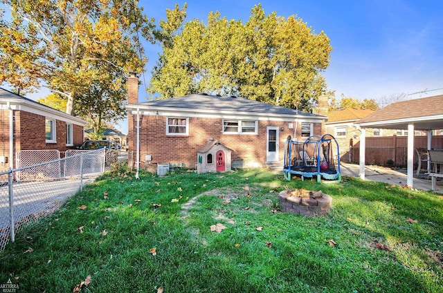 rear view of house featuring a trampoline and a lawn