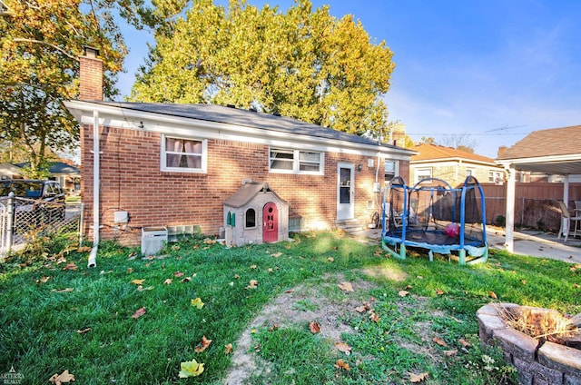 back of house with a yard and a trampoline