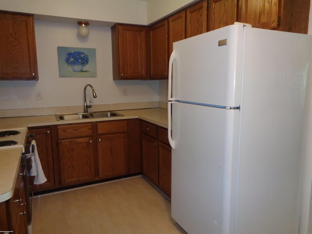 kitchen with white appliances, sink, and light wood-type flooring