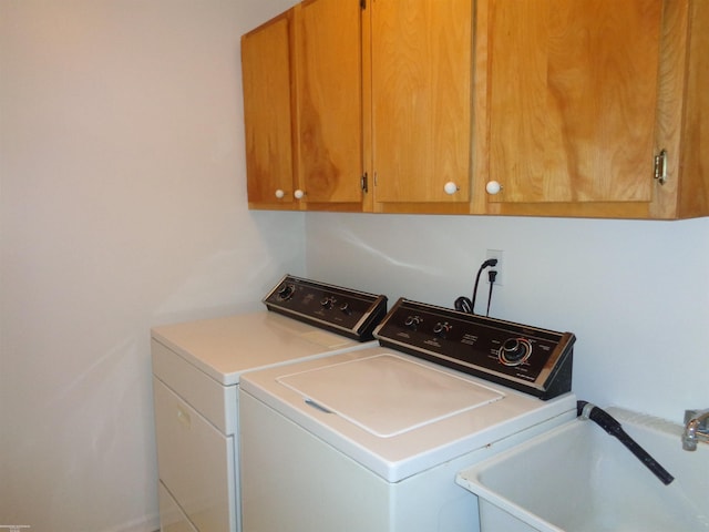 clothes washing area featuring sink, cabinets, and washing machine and clothes dryer