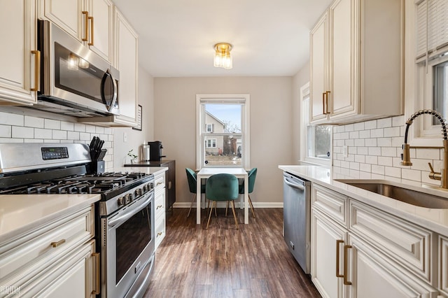 kitchen with appliances with stainless steel finishes, sink, backsplash, and dark hardwood / wood-style floors