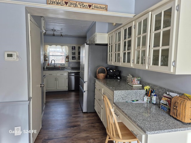 kitchen with sink, dark wood-type flooring, stainless steel appliances, light stone counters, and white cabinets