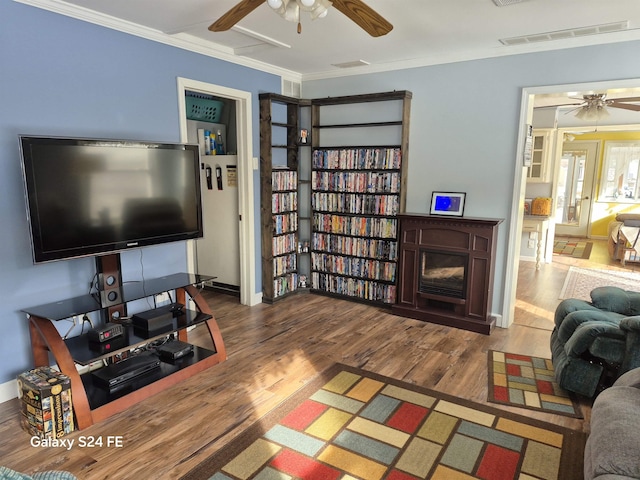 living room featuring ceiling fan, ornamental molding, and wood-type flooring