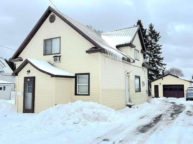 view of snowy exterior featuring a garage and an outdoor structure