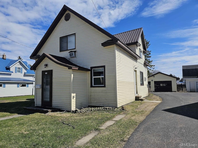 view of front of property with an outdoor structure, a garage, a front lawn, and metal roof