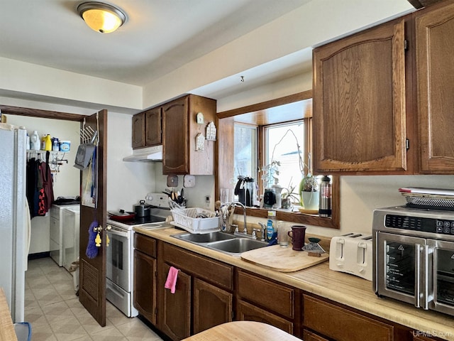 kitchen featuring light countertops, a sink, white appliances, independent washer and dryer, and under cabinet range hood