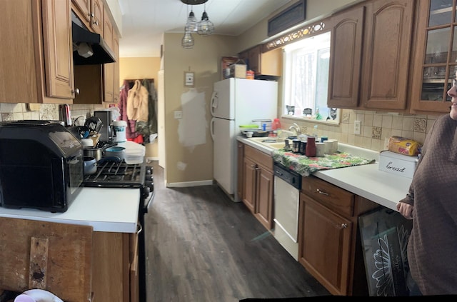 kitchen with dark hardwood / wood-style flooring, dishwasher, sink, and backsplash