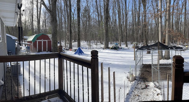 snow covered deck featuring a shed and central AC