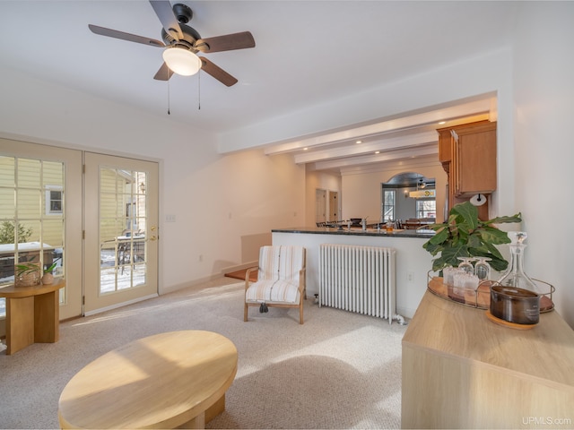 living room with baseboards, light colored carpet, radiator, ceiling fan, and beam ceiling