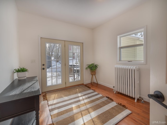 entryway featuring light wood-style floors, radiator, a healthy amount of sunlight, and baseboards