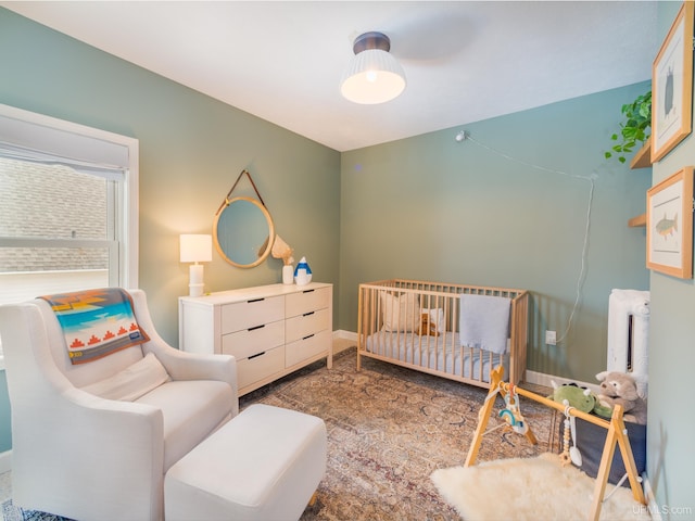 bedroom featuring a nursery area and baseboards