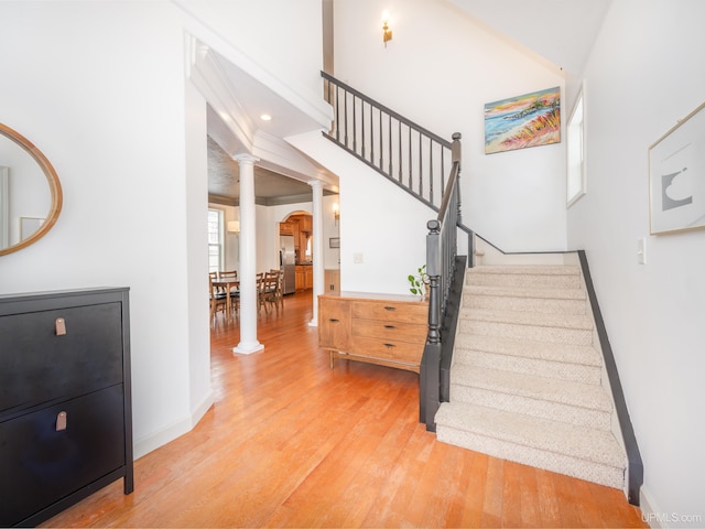 stairway with decorative columns and hardwood / wood-style flooring