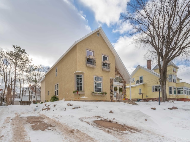 snow covered rear of property with stucco siding