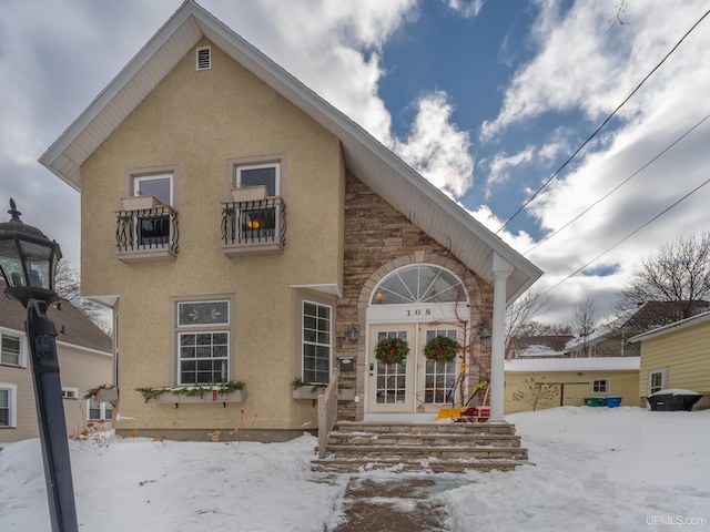 view of front of home featuring stone siding, french doors, and stucco siding