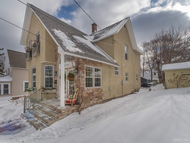 exterior space with stone siding, a chimney, and stucco siding