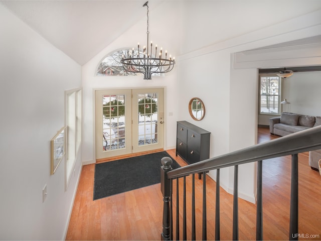 entryway with baseboards, high vaulted ceiling, wood finished floors, and an inviting chandelier