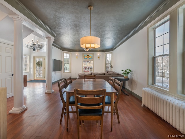 dining area with ornate columns, wood finished floors, and radiator