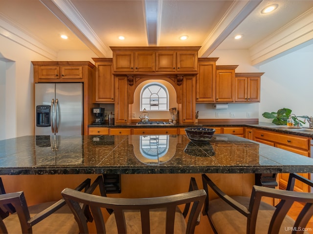 kitchen featuring crown molding, a large island, a breakfast bar area, stainless steel fridge, and beamed ceiling