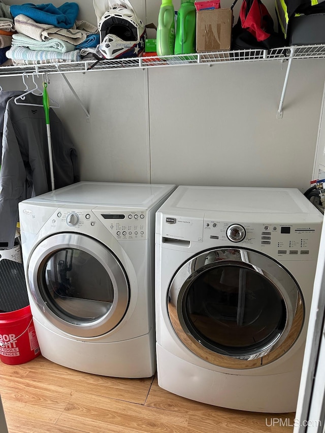 clothes washing area with wood-type flooring and washing machine and clothes dryer