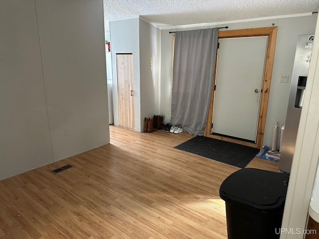 unfurnished room with ornamental molding, light hardwood / wood-style floors, and a textured ceiling