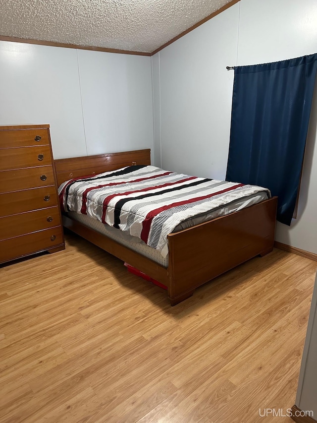 bedroom featuring crown molding, light hardwood / wood-style flooring, a textured ceiling, and vaulted ceiling