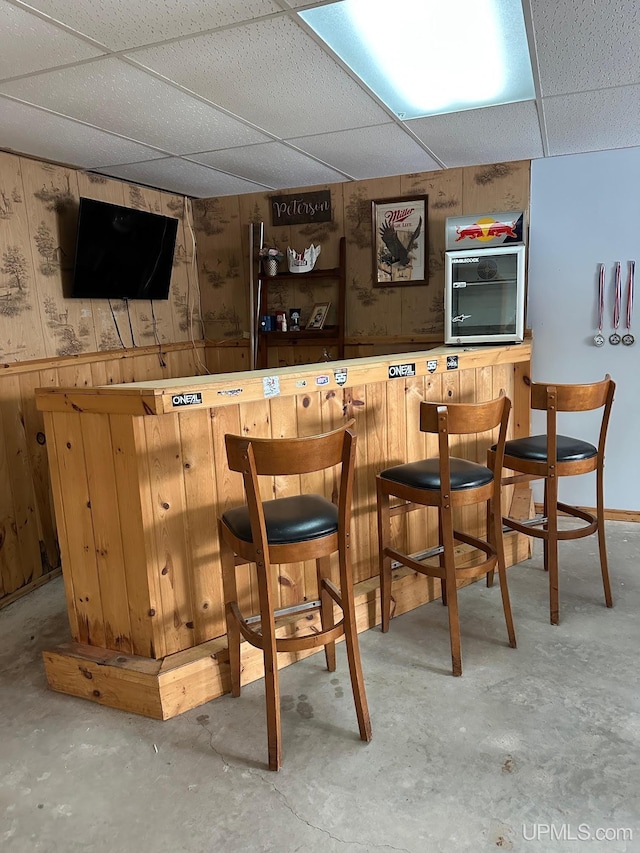 bar with a drop ceiling and wooden walls