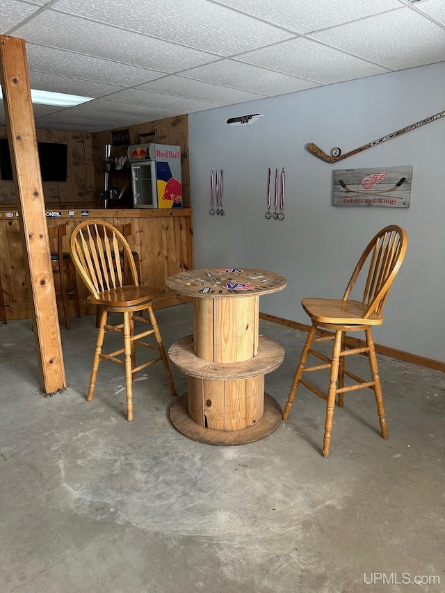 bar with a paneled ceiling and concrete floors