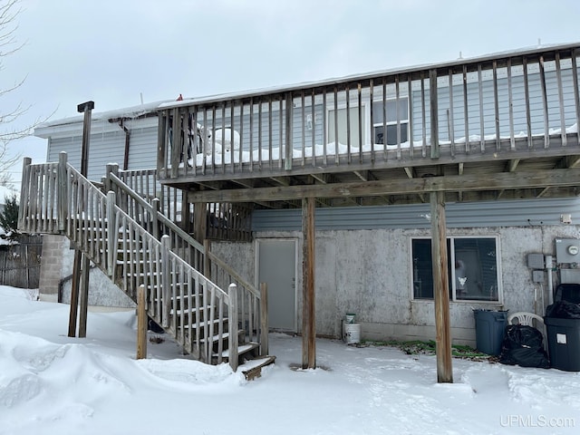 snow covered back of property featuring a deck