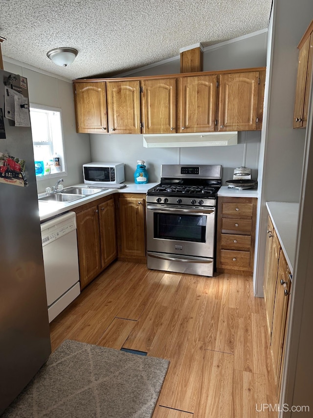 kitchen featuring sink, crown molding, stainless steel appliances, light hardwood / wood-style floors, and a textured ceiling