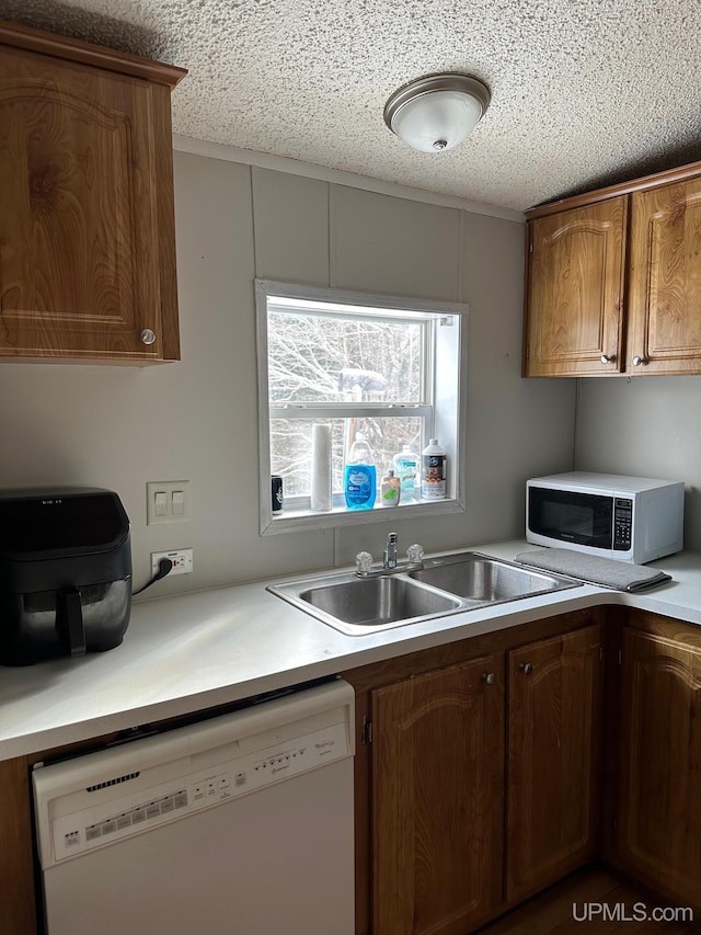 kitchen featuring sink, a textured ceiling, and white dishwasher