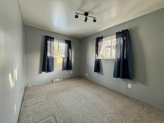 carpeted empty room featuring track lighting