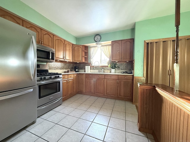 kitchen featuring backsplash, light tile patterned floors, sink, and appliances with stainless steel finishes