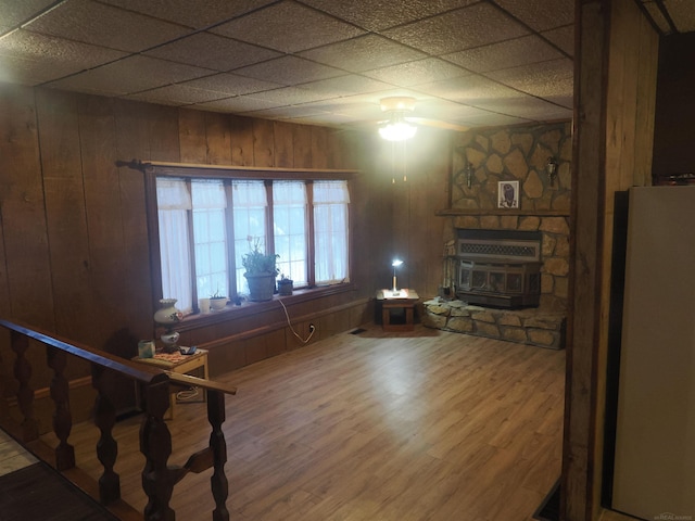 unfurnished living room with a paneled ceiling, wood walls, and wood finished floors