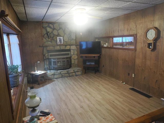 unfurnished living room with a paneled ceiling, wood walls, wood finished floors, and visible vents