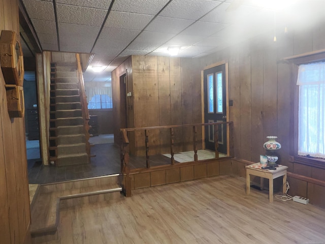 entrance foyer featuring stairway, wood finished floors, a paneled ceiling, and wooden walls