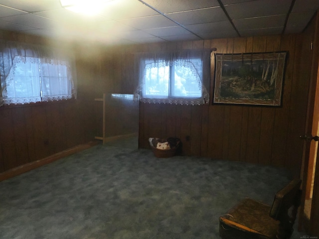 spare room featuring carpet floors, a drop ceiling, and wooden walls