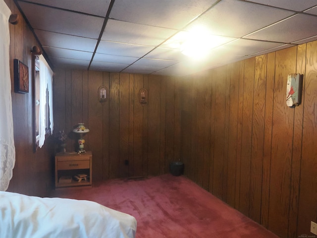 carpeted bedroom with a drop ceiling and wooden walls