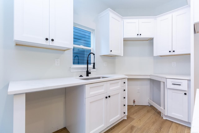 kitchen with light hardwood / wood-style floors, sink, and white cabinets