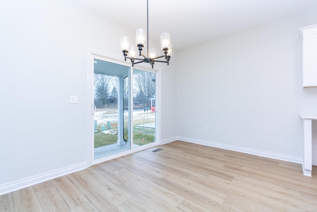 unfurnished dining area featuring an inviting chandelier and light wood-type flooring