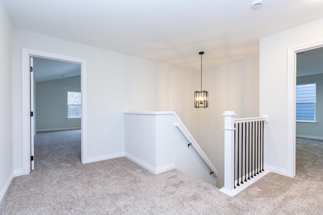 stairs featuring an inviting chandelier and carpet floors