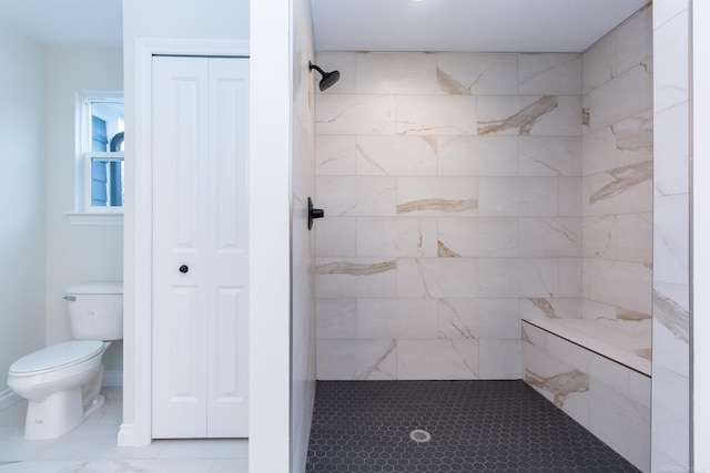 bathroom with a tile shower and toilet