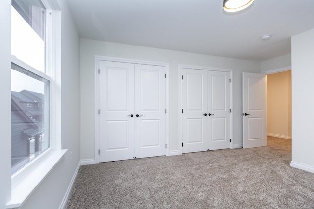 unfurnished bedroom featuring light colored carpet and two closets