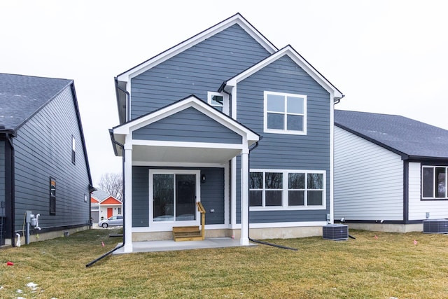 rear view of property with central AC unit and a yard