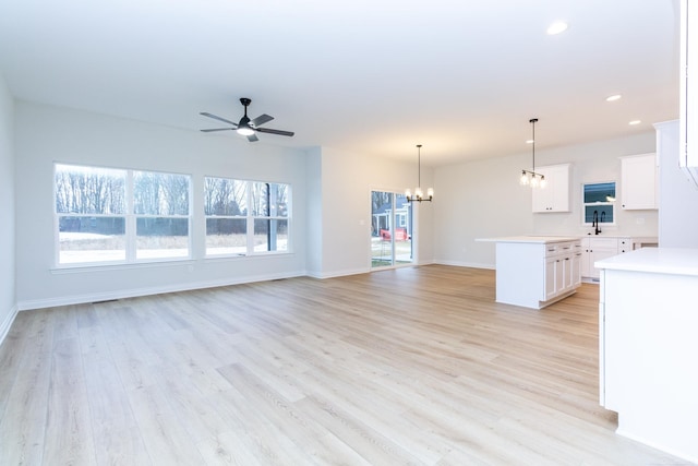 unfurnished living room featuring sink, ceiling fan with notable chandelier, and light hardwood / wood-style floors