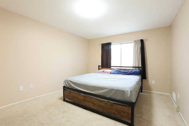 bedroom with light carpet and baseboards