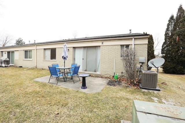 rear view of house featuring cooling unit, brick siding, a lawn, and a patio