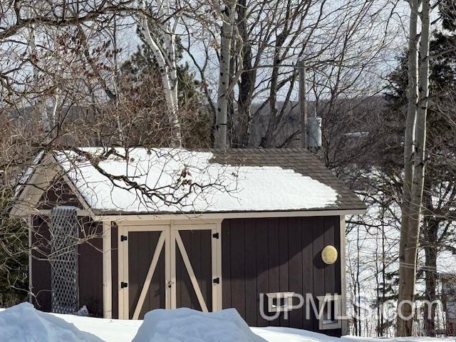 snow covered structure featuring an outbuilding