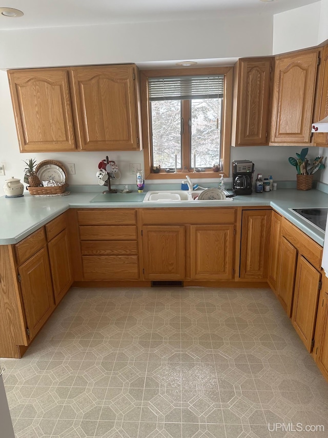 kitchen with black electric stovetop, visible vents, light countertops, and a sink