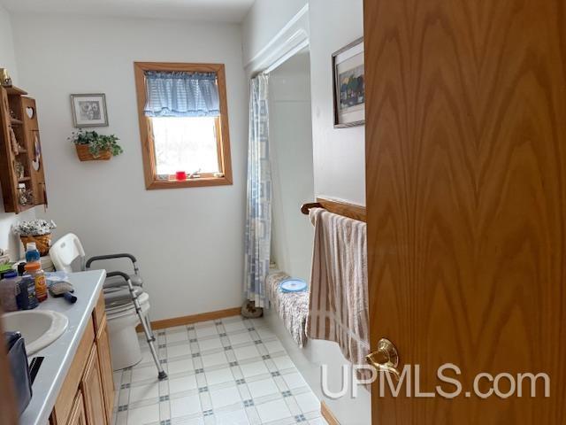 bathroom with toilet, vanity, baseboards, and tile patterned floors