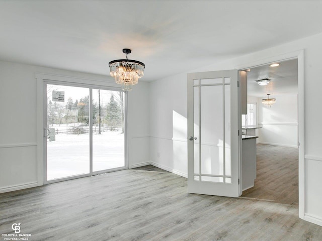 unfurnished dining area with an inviting chandelier and light hardwood / wood-style flooring